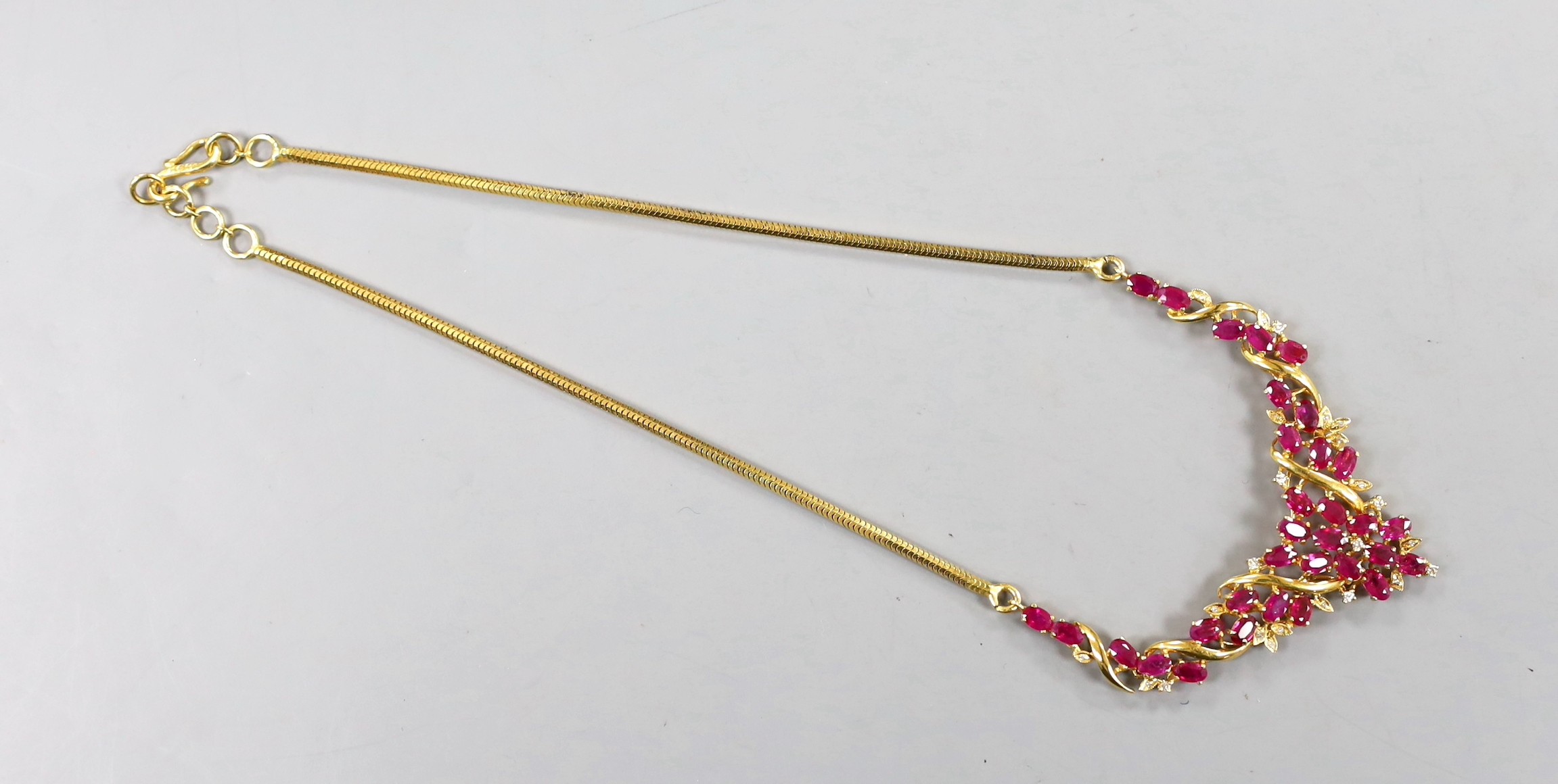 A modern Thai yellow metal, oval cut ruby and diamond chip cluster set necklace, 40cm, gross 22.6 grams.